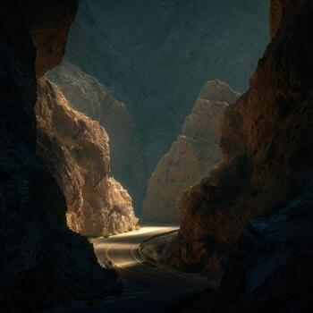 A road winding through a canyon with light shining through the rocks photo