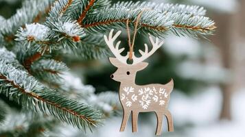 Wooden christmas reindeer ornament hanging on snowy pine tree branch photo