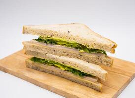 Classic Chicken Caesar Sandwich with Fresh Lettuce on Seeded Bread on wooden board side view of fast food on white background photo