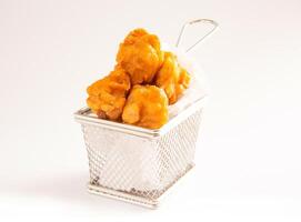 Crispy Golden Chicken Nuggets in Mini Metal Frying Basket on White Background side view of popular snack photo