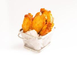 Crispy Golden Chicken Wings with Sweet and Sour Sauce in Frying Basket on white background side view of Appetizing Snack photo