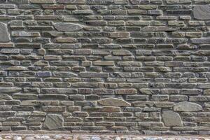 The wall of the castle is made of uneven, flat stones of various dark shades. Abstract background. photo