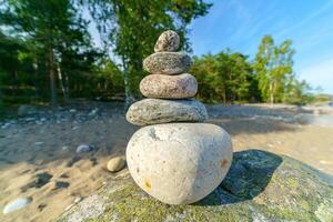 A pyramid of stones on the shore. Unstable balance of stone objects. photo