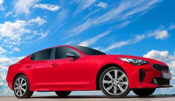 Red car on a blue sky background with white clouds. A modern, bright image of an avto mobile for design solutions. photo