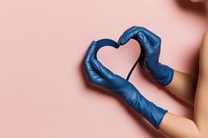 Hands in Blue Gloves Shape a Heart Symbol With a Blue Ribbon Against a Pink Background photo