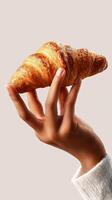 Delicious Croissant Held by a Hand Against a Simple Background in a Cozy Setting photo