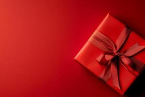 Gift Wrapped in Red Ribbon on Vibrant Red Background for Celebrations or Special Occasions photo