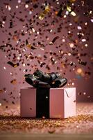 Colorful Confetti Falling Around a Pink Gift Box With a Black Ribbon on a Festive Background photo