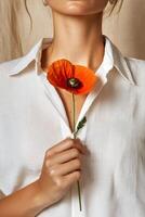 Woman Holding Vibrant Orange Flower While Dressed in a White Shirt Indoors photo