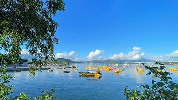 Fishing, recreational boats, natural background with trees, clouds, blue sky and mountains photo