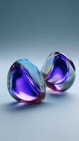 Two smooth, iridescent, abstract glass shapes in shades of purple and blue rest on a soft gradient background, creating a visually appealing and modern composition photo