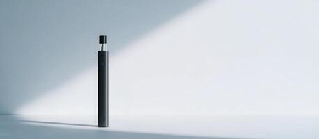 Sleek black vape pen standing vertically, casting sharp shadows under dramatic lighting against pristine white backdrop photo