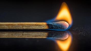 Macro shot of a wooden matchstick ignited with a fiery, blue-orange flame. photo