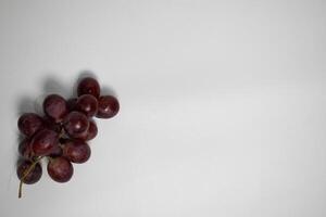 Minimalist top-down portrait of grapes placed on the left side of a plain background. photo