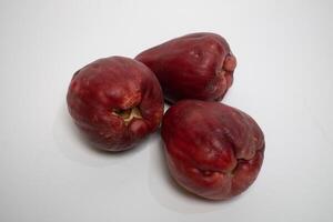 Three Jamaican guavas arranged on a clean white surface, showing off their unique shape. photo