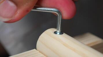 Screwing a bolt into a wooden piece during assembly process video
