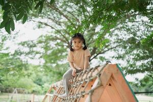 Young girl exploring playground equipment in a beautiful outdoor park surrounded by green trees and nature, enjoying childhood adventures and playtime fun photo
