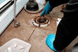 Close-up image showing a plumber replacing the wax ring seal at the base of a toilet with copy space. photo