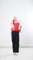 Indonesia independence day celebration with Asian girl wearing red and white Indonesia flag color attribute talking on the phone call and showing OK sign with hand gesture isolated on white background photo