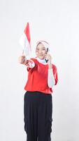 Indonesia independence day celebration with Asian girl wearing red and white Indonesia flag color attribute talking on phone call while showing Indonesia flag decoration isolated on white background photo