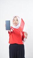 Indonesia independence day celebration with happy Asian girl wearing red and white Indonesia flag color attribute showing blank screen smartphone to camera isolated on white background photo