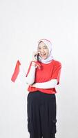 Indonesia independence day celebration with happy Asian girl wearing red and white Indonesia flag color attribute talking on the phone call isolated on white background photo