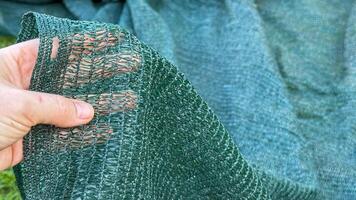 Hand gently holds intricately woven shade cloth, perfect for DIY projects, Urban Gardening Week, microclimate creation, sustainable design photo