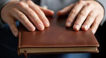 Hands rest on a brown leather notebook, ready for writing photo