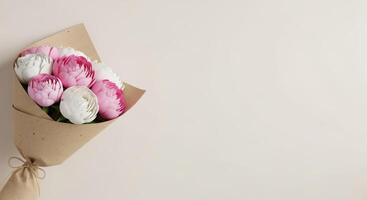 A charming bouquet of pink and white ranunculus wrapped in craft paper photo