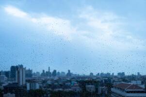 Raindrops on glass with soft city silhouette when monsoon season background. photo