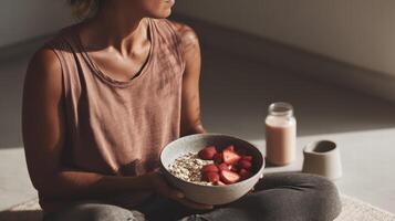Athletic woman holding bowl of oatmeal topped with fresh strawberries in soft natural light photo