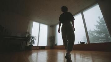 Young woman standing in spacious room with large windows and wooden floor, calm mood photo