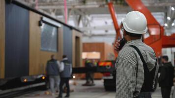 Construction supervisor communicating with walkie talkie in prefabricated housing factory video