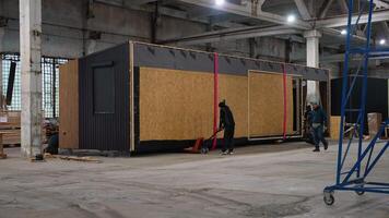 Workers moving prefabricated tiny house module in factory. Ternopil, Ukraine - 1 February 2025 video