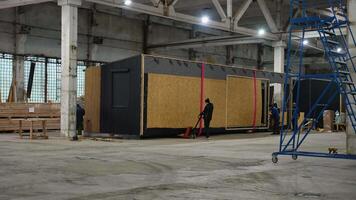 Workers moving prefabricated tiny house module in factory. Ternopil, Ukraine - 1 February 2025 video
