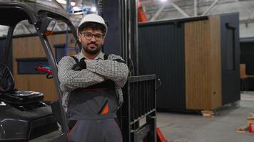 Confident industrial forklift operator posing with crossed arms in factory video
