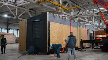 Construction workers positioning prefabricated tiny house in factory. Ternopil, Ukraine - 1 February 2025 video