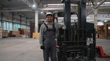 Smiling warehouse worker giving thumbs up next to forklift video