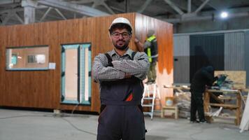 Construction worker smiling with crossed arms in prefabricated house factory video