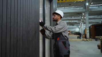 Construction worker applying sealant on wall paneling in factory video