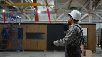 Construction worker communicating with walkie talkie in prefabricated house factory video
