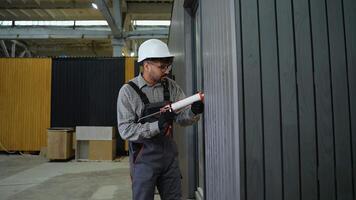 Construction worker applying sealant on wall in factory video