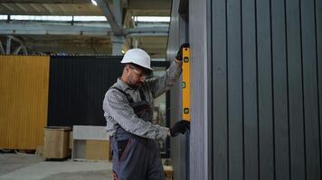 Construction worker checking verticality of modular house wall video