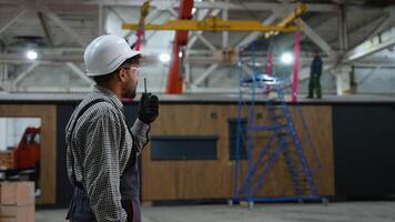 Engineer communicating with walkie talkie and giving instructions in factory video