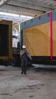 Engineer walking and talking on walkie talkie in warehouse with prefabricated house loaded on truck video