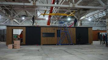 Engineers installing roof panel on modular house in factory video