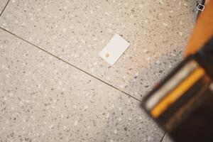 Card dropped on tiled floor near wallet during busy day photo