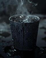 Steaming black coffee in a dark cup with water droplets on surface photo