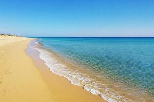 Aerial view of endless sandy beach with crystal clear turquoise water and clear blue sky, perfect atmosphere for rest and relaxation. For travel, vacation, nature, summer, serenity and coastal themes. photo