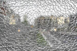 Shattered glass window forming intricate web like cracks photo
